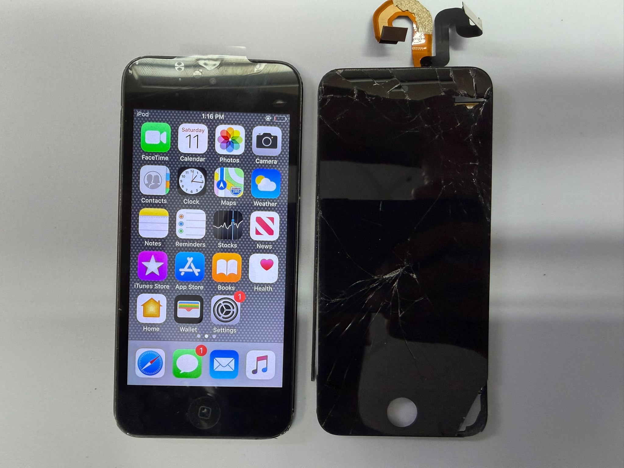 Completed iPod Touch screen repair at Charlotte Tech Repair — repaired iPod Touch powered on showing the iOS home screen, next to the shattered screen assembly that was removed