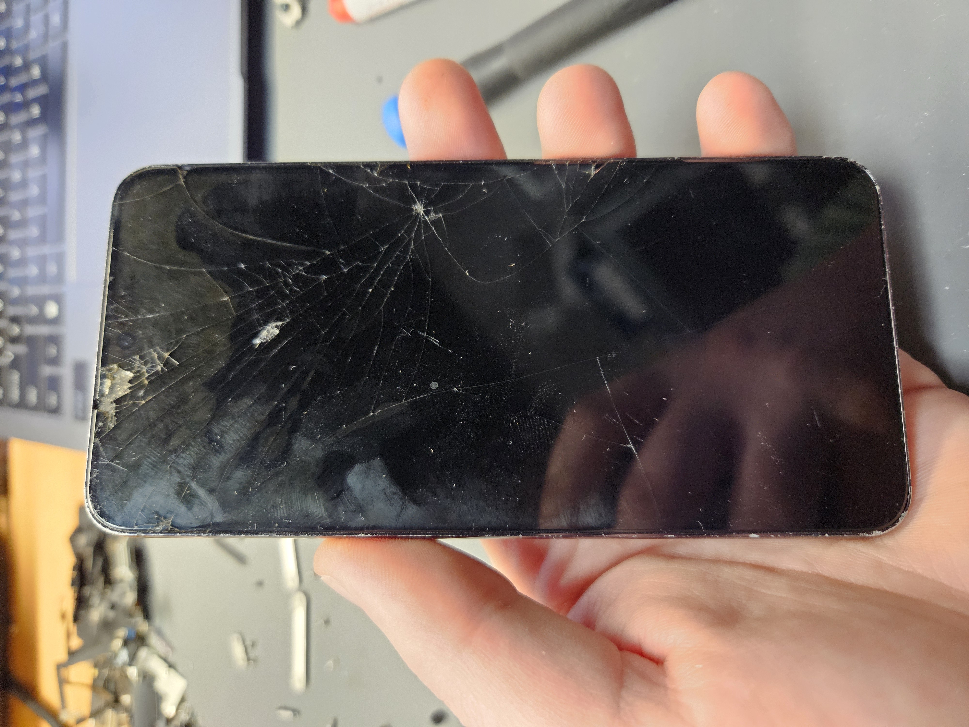 Samsung Galaxy S23 FE with a badly cracked screen before repair, spider-web cracking across the display