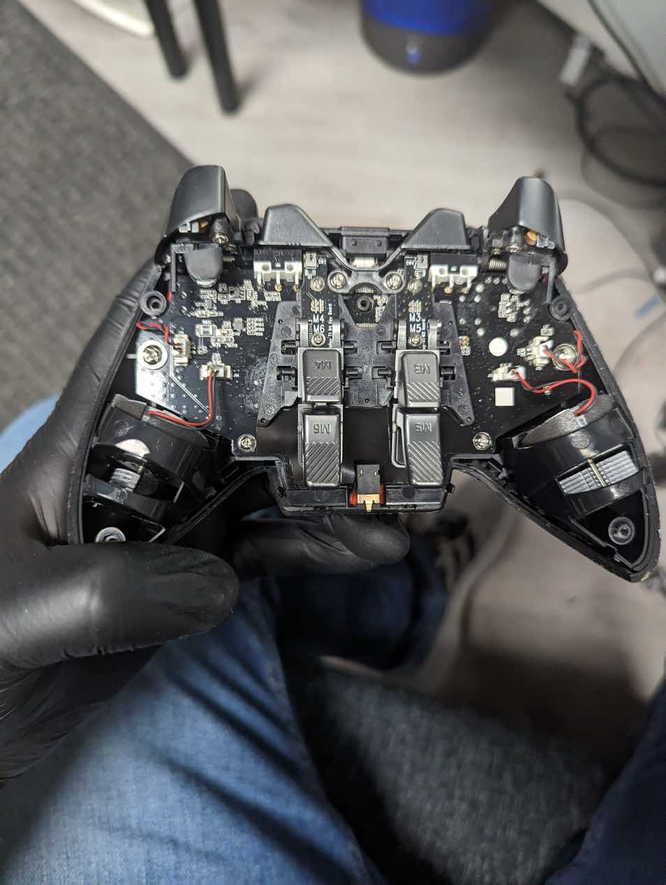 Custom aftermarket Xbox controller opened during stick drift repair at Charlotte Tech Repair — rear shell removed exposing modded PCB with four programmable back paddles and custom wiring