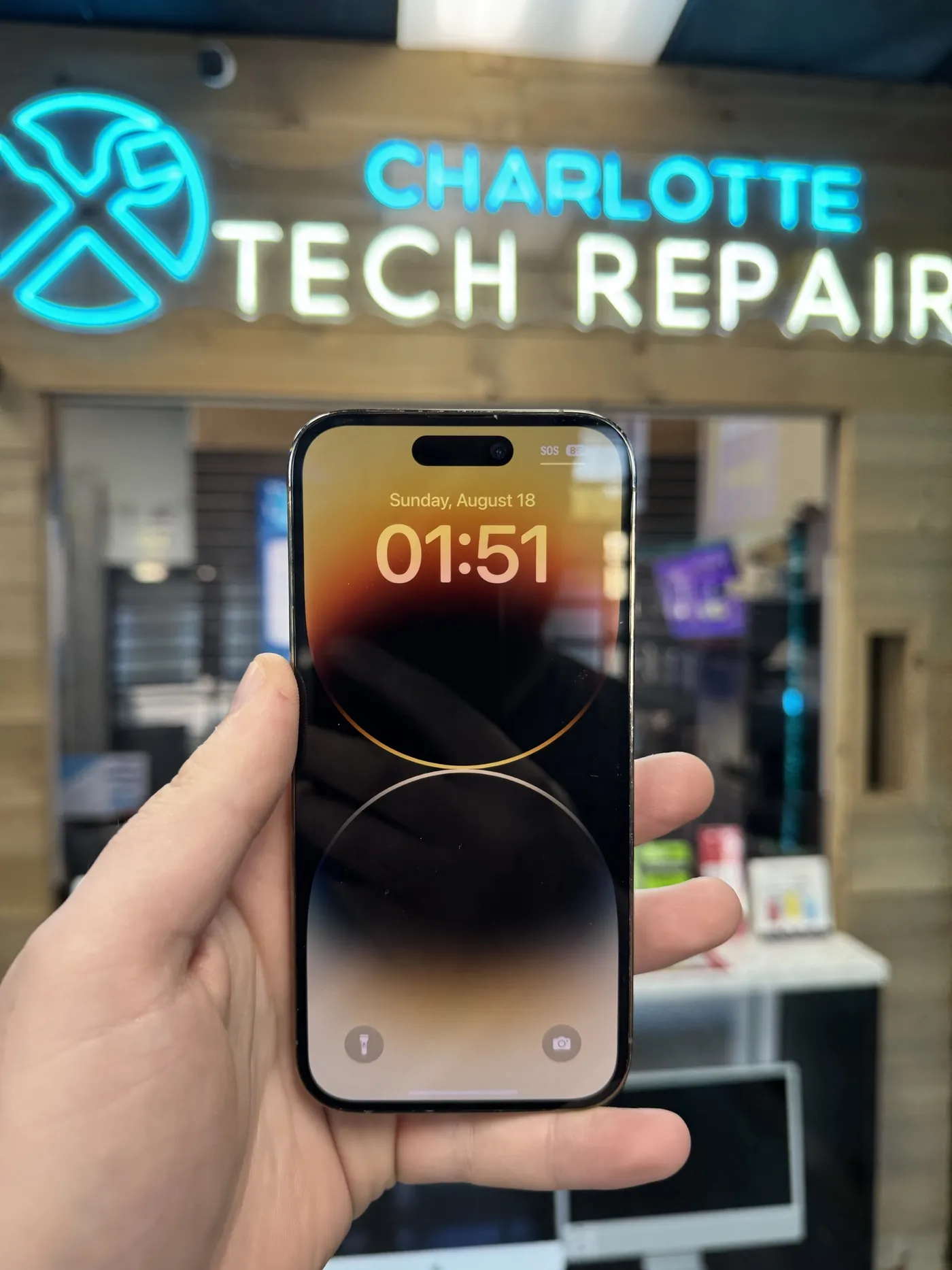 A repaired iPhone 14 Pro in front of the Charlotte Tech Repair sign